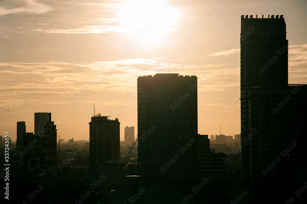beautiful warm toned color of sky  and the sun on a top of silhouette buildings  in  a city .photo with some noise and gain