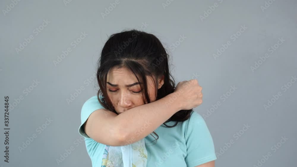 Sick young woman is coughing into her sleeve or elbow to prevent spread Covid-19, Corona virus Sick young woman is coughing into her sleeve or elbow to prevent spread Covid-19, Corona virus