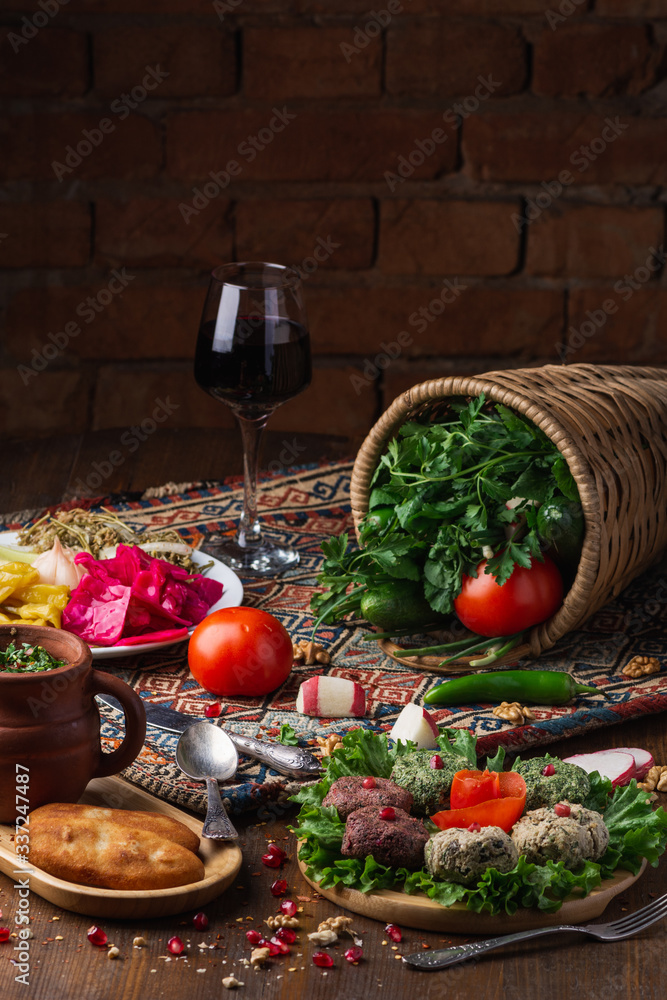 Traditional georgian meals, aubergine rolls, lobio boiled beans with spices, greens, tomato, cucumber and wine is served for lunch or dinner on wooden table. Traditional georgian meals, aubergine rolls, lobio boiled beans with spices, greens, tomato, cucumber and wine is served for lunch or dinner on wooden table.