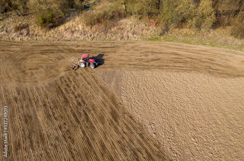 aerial shot of Farmer in tractor preparing land with seedbed cultivator, morning sun