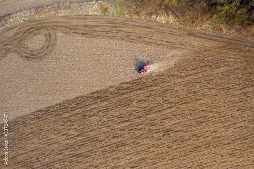 aerial shot of Farmer in tractor preparing land with seedbed cultivator, morning sun