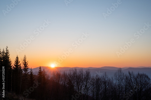 sunrise in the mountains with trees in the foreground