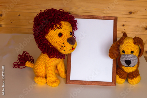 Ð¡opyspace for text in a frame for congratulations, next to an amigurumi doll is a lion and dog. photo