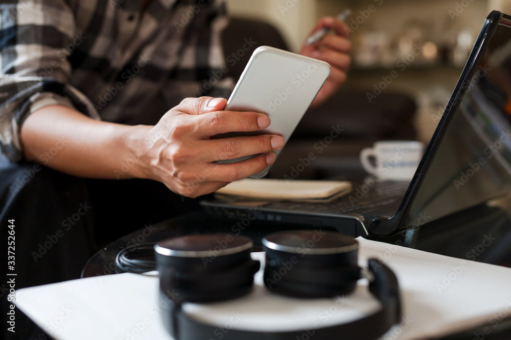 a businessman working from home holding a smartphone to checking dairy planning to prepare meeting with a team by video conference on laptop at home office. a businessman working from home holding a smartphone to checking dairy planning to prepare meeting with a team by video conference on laptop at home office.