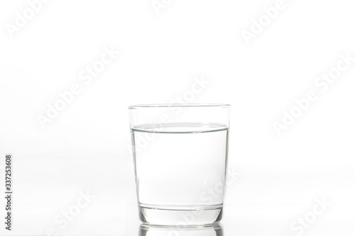 Glass with water and ice on a white background. Glass of mineral water and ice on white background.