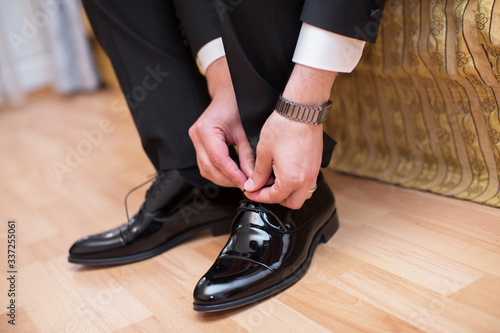Closeup view of male hands lacing beautiful elegant shoes. wedding day. groom tie his shoe . Man wearing a suit putting his brown shoes on. Hands and shoe close-up.