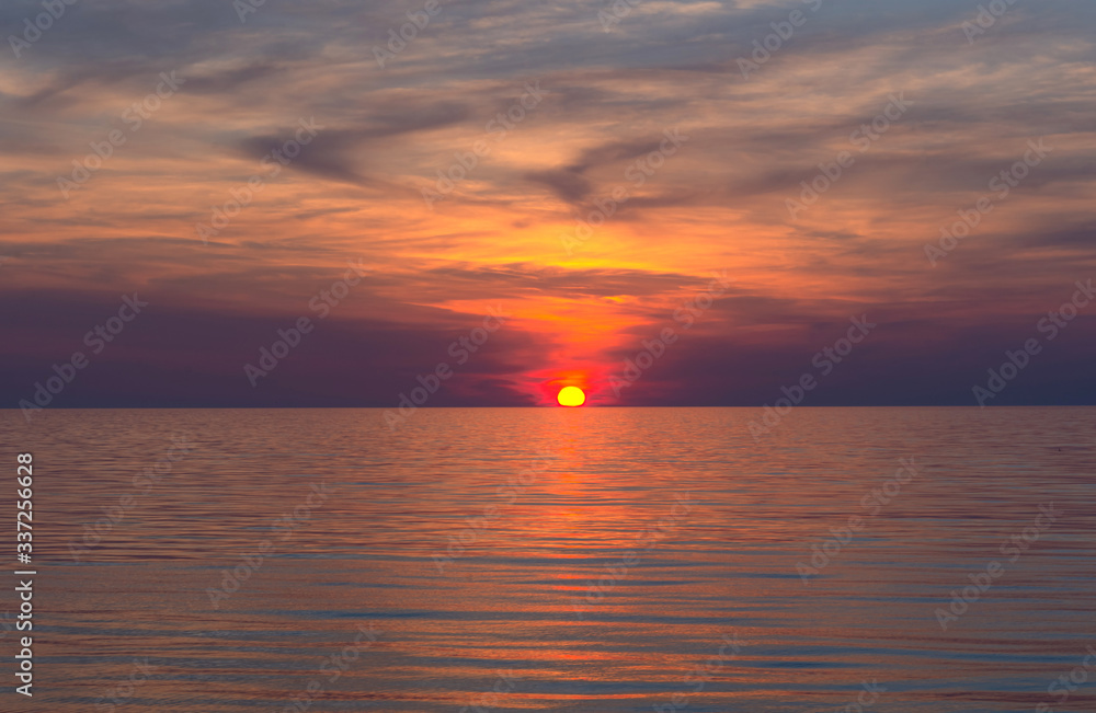 Beautiful clouds over the calm sea. Pink sunset on the sea. Bright natural background