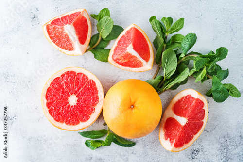 Red grapefruit with slaces and mint leaves on a light background