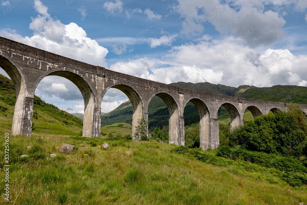 The landscape with famous Glenfinnan Viaduct in Scotland in perspective view from bottom with blue sky and clouds