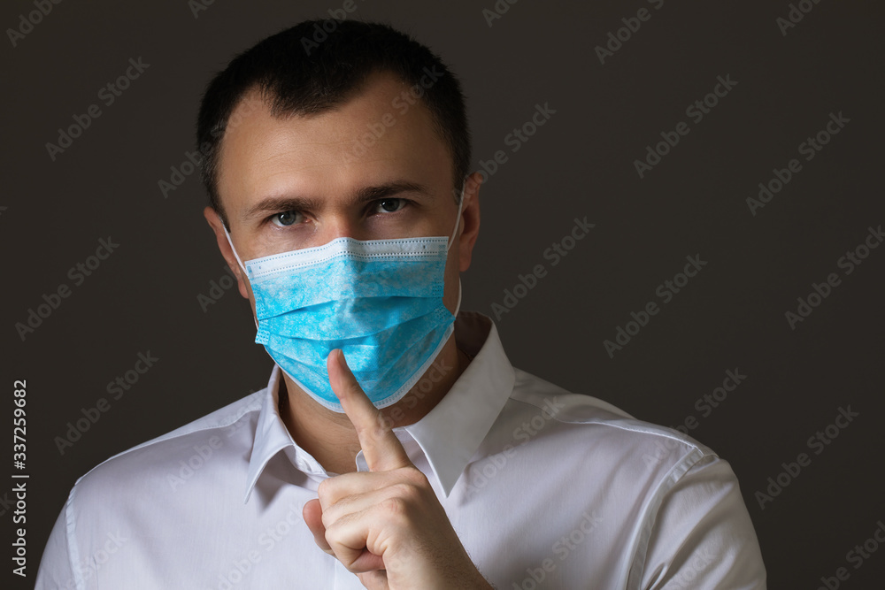 The masked man shows a sign of silence. The concept of coronavirus is a real threat or mass hysteria The masked man shows a sign of silence. The concept of coronavirus is a real threat or mass hysteria