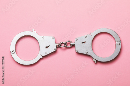 Closed handcuffs on a pink background. Top view on special equipment