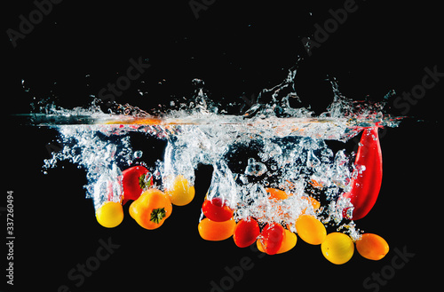Sweet peppers, fresh vegetables falling into water splash
