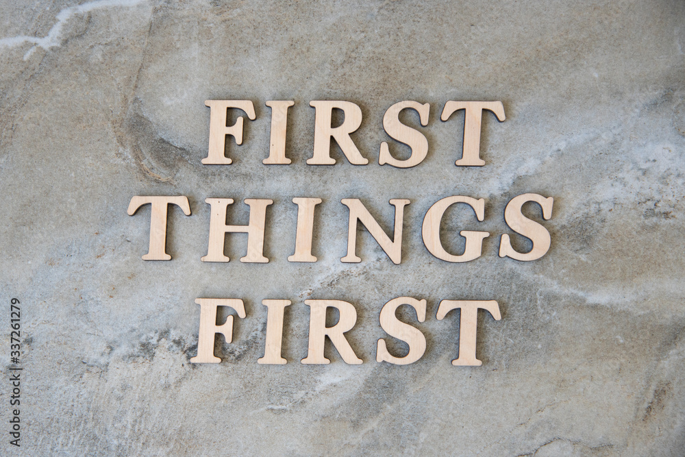 first things first , writen wooden letters on stone background first things first , writen wooden letters on stone background