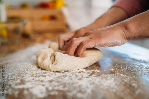 Woman kneading the dough to make a pizza in her home kitchen