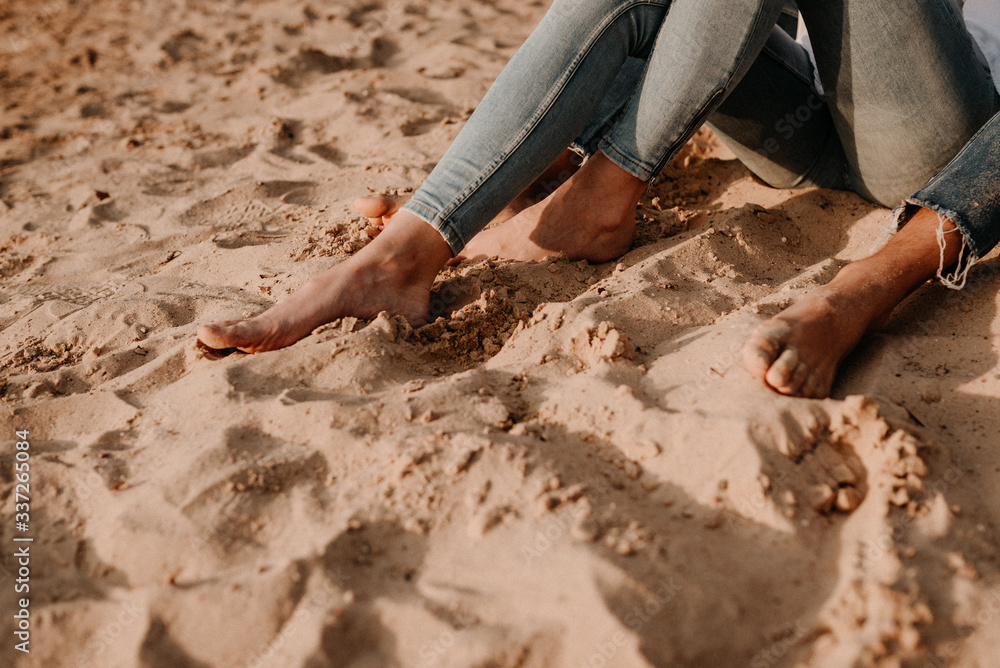 barefoot couple with jeans in sand. barefoot couple with jeans in sand.