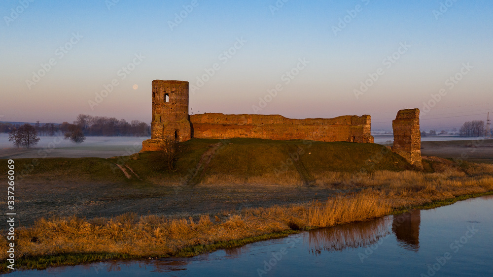 Ruiny zamku w Kole z drona o wschodzie słońca nad Wartą we mgle