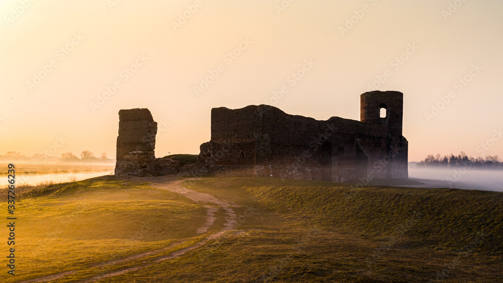 Ruiny zamku w Kole z drona o wschodzie słońca nad Wartą we mgle - obrazy, fototapety, plakaty 