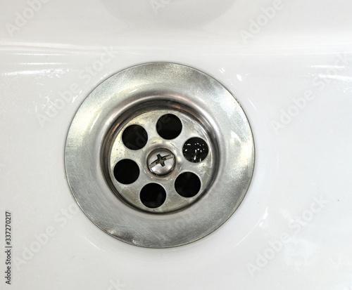 Draining water with a stainless steel grate in an old, long-used bathroom sink