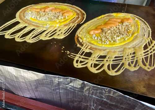 Mini pancake roll stuffed with pork and sausage are cooking on the pan.