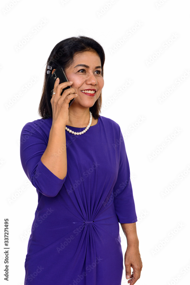 Studio shot of happy mature Asian woman talking on mobile phone isolated against white background Studio shot of happy mature Asian woman talking on mobile phone isolated against white background