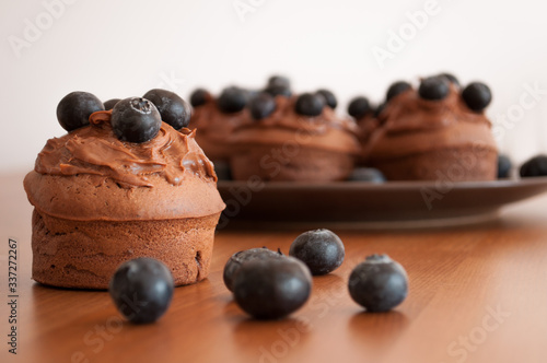 Obraz na płótnie Czekoladowe muffiny z jagodami na drewnianym stole.
