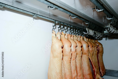 A lot of chopped raw pork meat hanging and arrange and processing deposit in a refrigerator, in a factory. photo