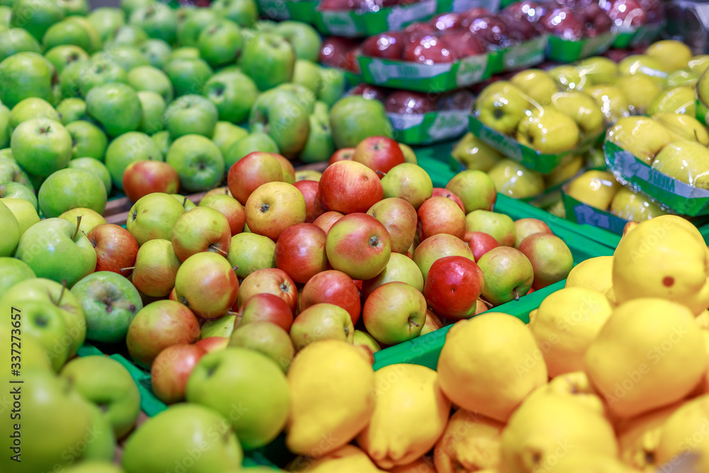 green, yellow and red apples on a counter in a store green, yellow and red apples on a counter in a store