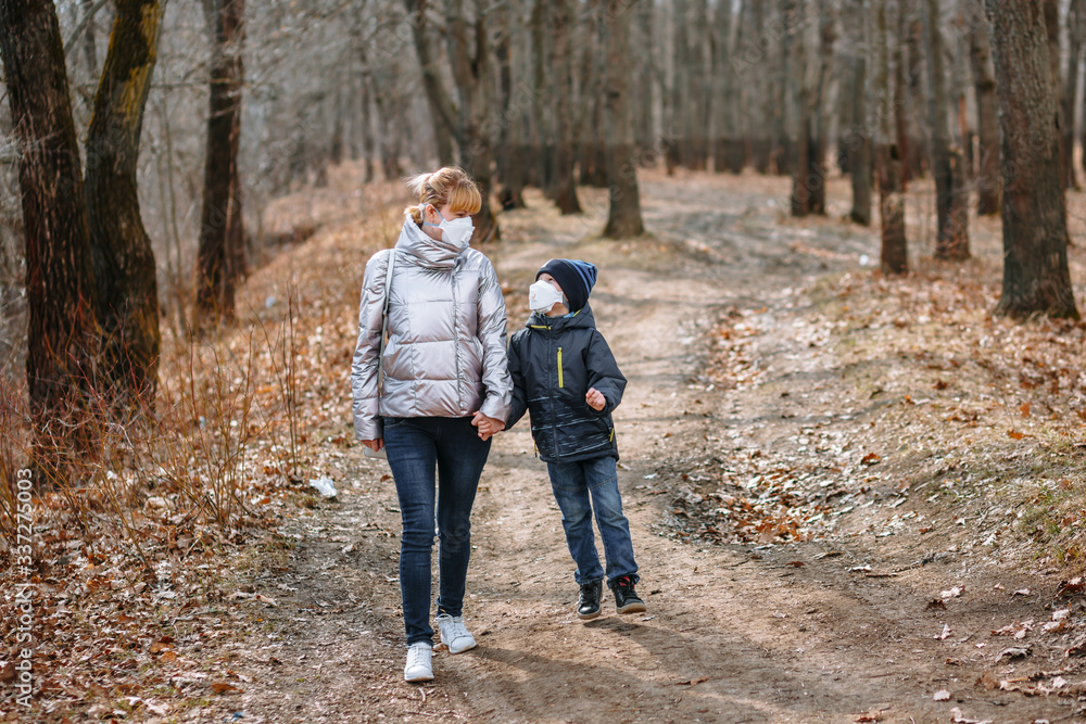 A girl with her son in sanitary masks on a walk in the Park A girl with her son in sanitary masks on a walk in the Park