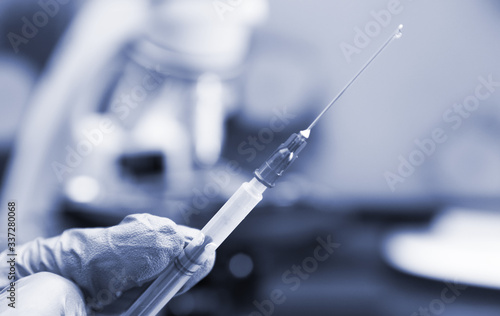 Virologist's hand in glove holding syringe.