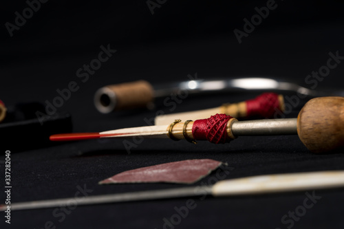 Bassoon reeds inside a box on a black background along with tools.
