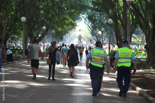 Procession of people including two police officers walking down a path in Hyde Park on their way to the Climate Change Strike at the Domain in Sydney Australia