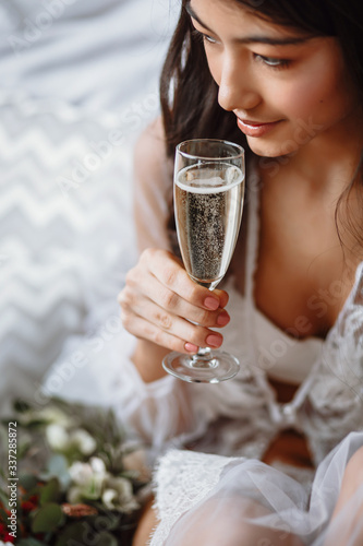 bride in her underwear with a glass of champagne on the bed