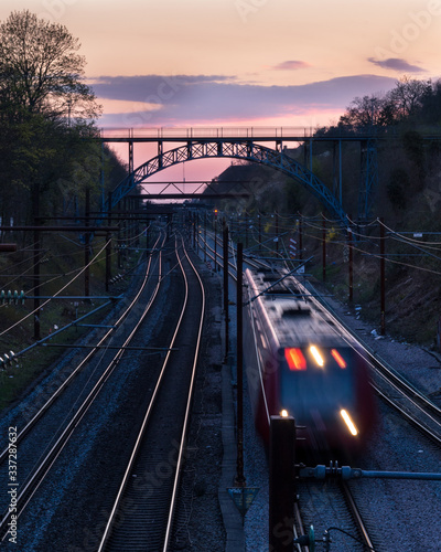 Train after sunset in Copenhagen with bridge in the background. 