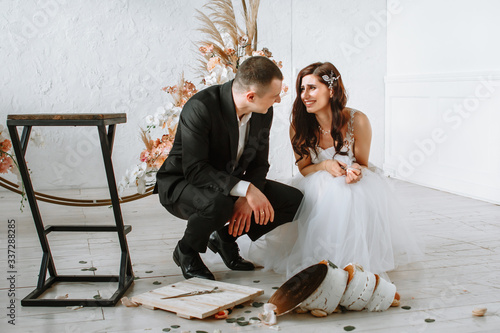 Three-tiered wedding cake falling from the table. Emotions of the bride and groom when the cake falls