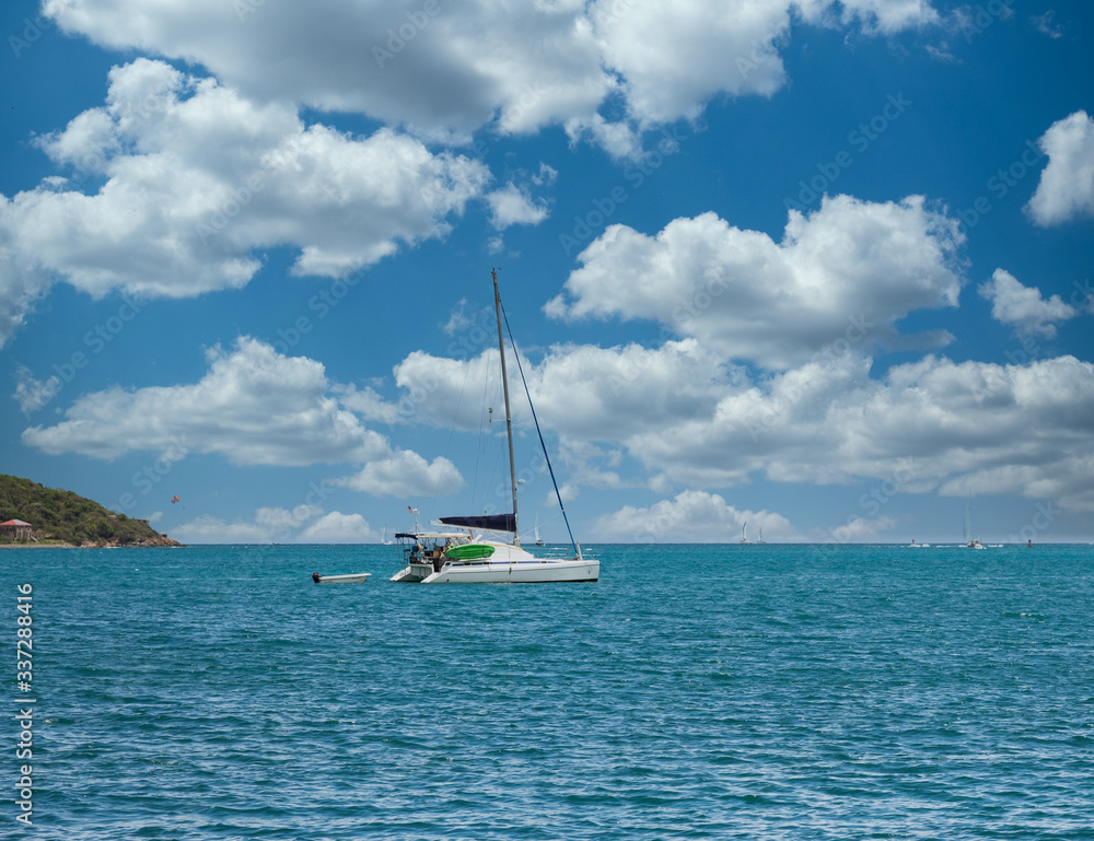 A white sailboat with empty mast on blue water in the Caribbean