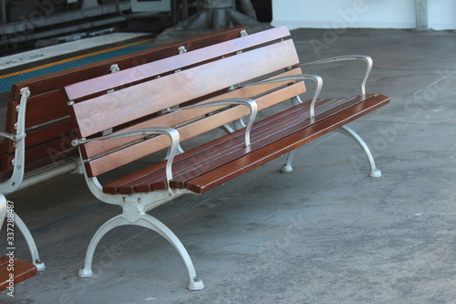 Fototapeta Naklejka Na Ścianę i Meble -  Example of hostile design or aggressive industrial design. A timber and metal bench seat at a train station with four arm rests. The design prevents the homeless from laying down.