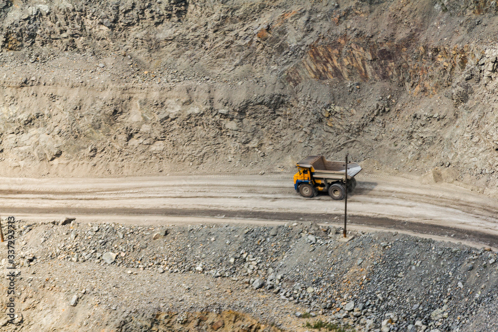 A daytime general view of the iron ore quarry. In sunny weather. Apparently, special equipment is used. Larger trucks transport ore. Tipper trucks transport iron ore. A daytime general view of the iron ore quarry. In sunny weather. Apparently, special equipment is used. Larger trucks transport ore. Tipper trucks transport iron ore.