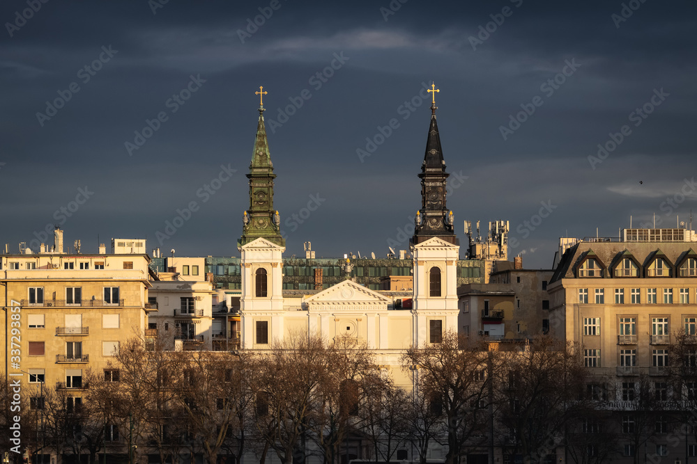 Last sun rays on Cathedral of Our Lady in Budapest with dark blue clouds on the background