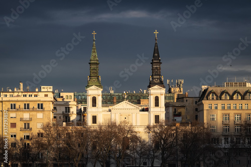 Obraz na płótnie Last sun rays on Cathedral of Our Lady in Budapest with dark blue clouds on the background w salonie