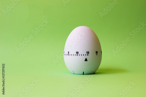 white egg timer on green background. Happy Easter in the kitchen. Home related, home staying. Free copy space. photo