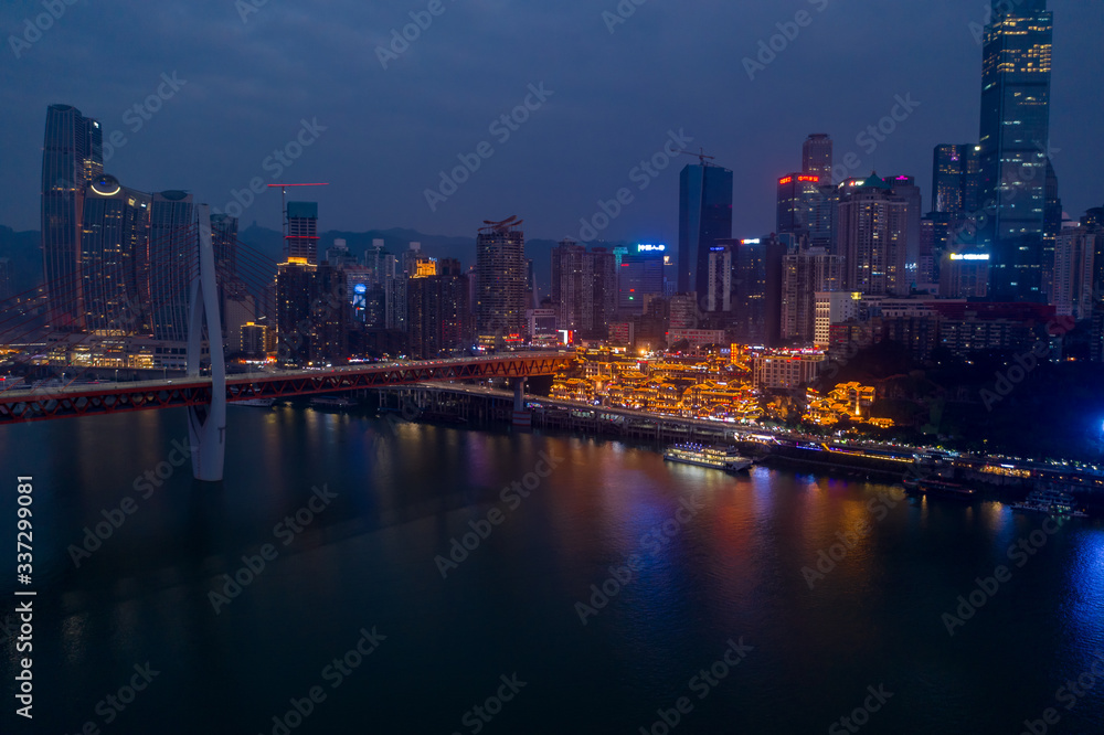 Aerial dusk view of Hong Ya dong Cave, Historic Chinese folk religion town with light on by Jialing River skyscrapers
