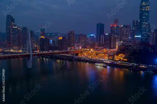 Aerial dusk view of Hong Ya dong Cave, Historic Chinese folk religion town with light on by Jialing River skyscrapers © Davidzfr