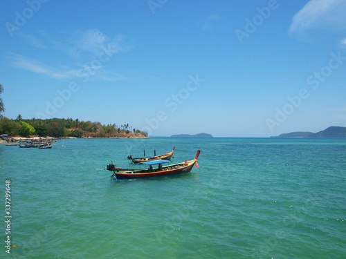 Longtail boats anchored near coast of tropical island. Traditional longtailboat in Thailand. Old fishing asian wooden boat. Panorama of beautiful sea and green islands. Azure clean transparent water 