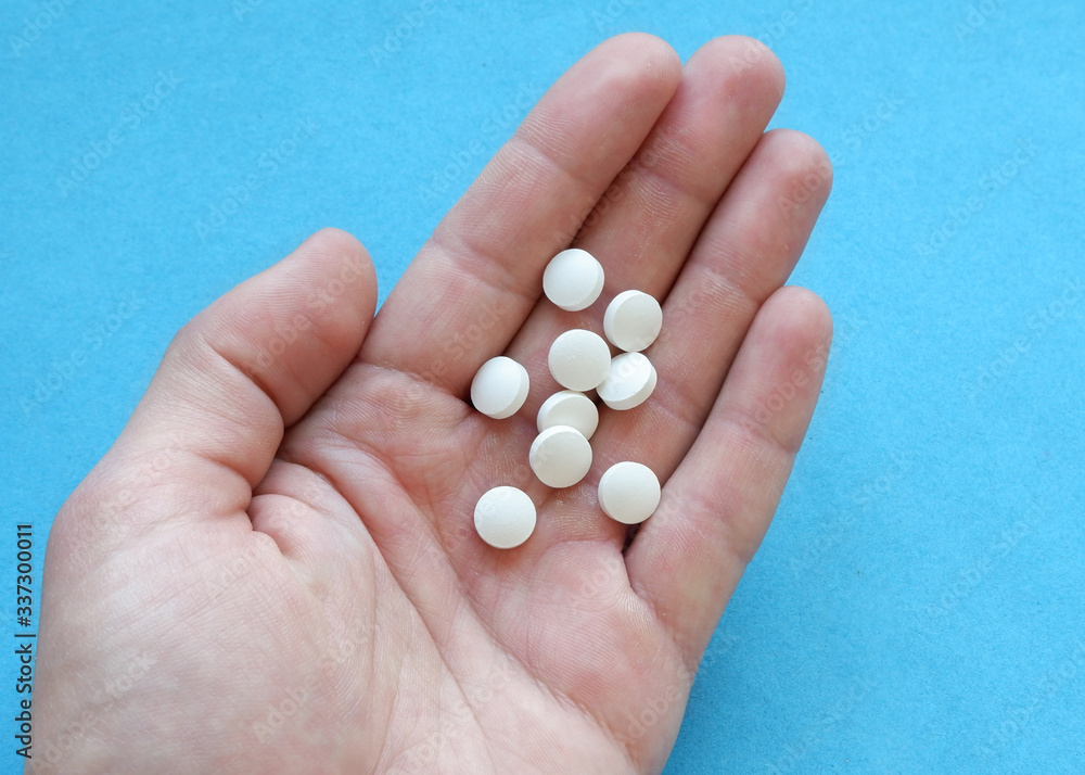 Male hand holds white medicinal pills in the palm of your hand. Male hand holds white medicinal pills in the palm of your hand.