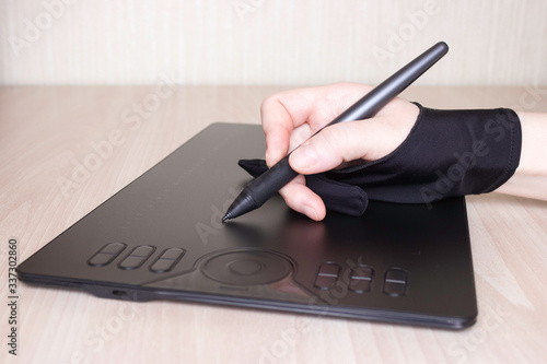 A woman's hand in a special glove draws on a graphics tablet. Side view, tools for graphic drawing. photo