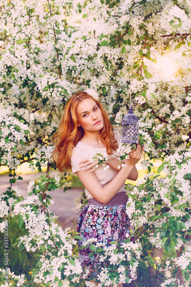 Model with red hair posing in a blooming apple tree. Model with red hair posing in a blooming apple tree.