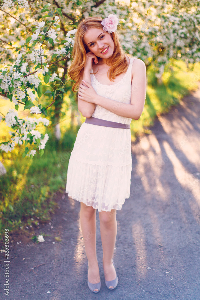 Model with red hair posing in a blooming apple tree. Model with red hair posing in a blooming apple tree.