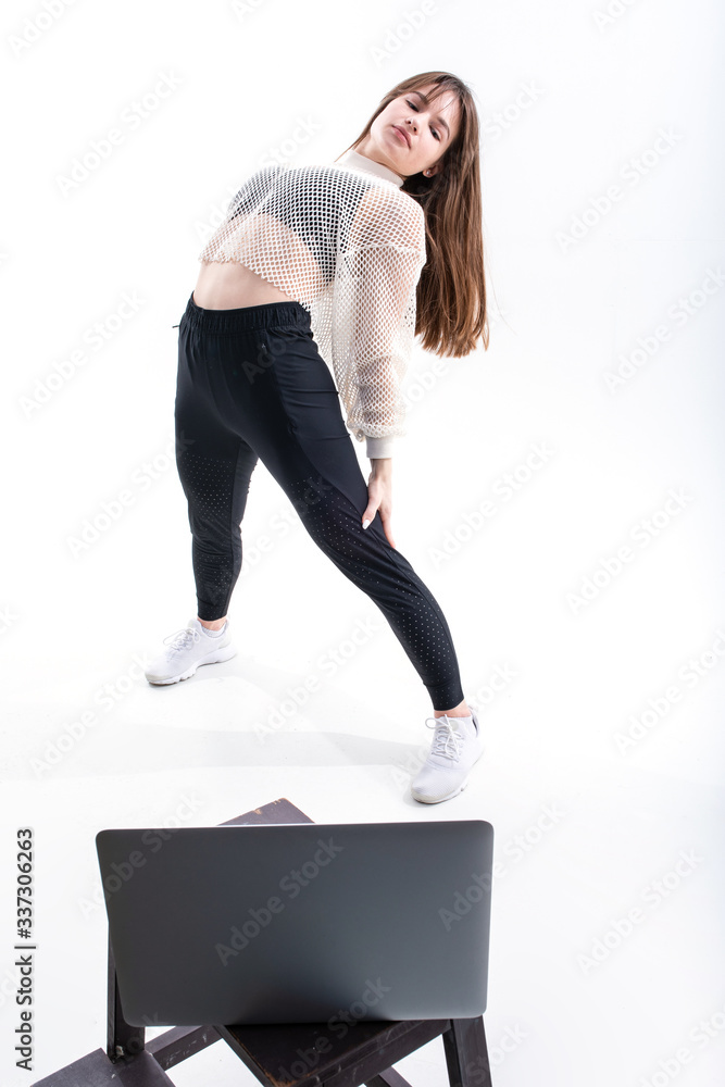 Athletic girl trains online watching videos on a laptop on a white background Athletic girl trains online watching videos on a laptop on a white background