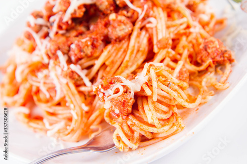 Spaghetti bolognese on a plate  sprinkled with cheese eaten with a fork
