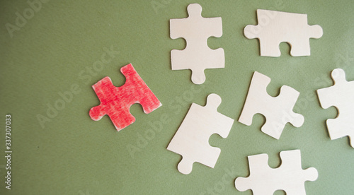 Red puzzle and white pieces of puzzles on a green background. Leadership strategy. Business ideas. Home schooling. Strategy stand out, marketing concept, social media influencers, HR recruiter